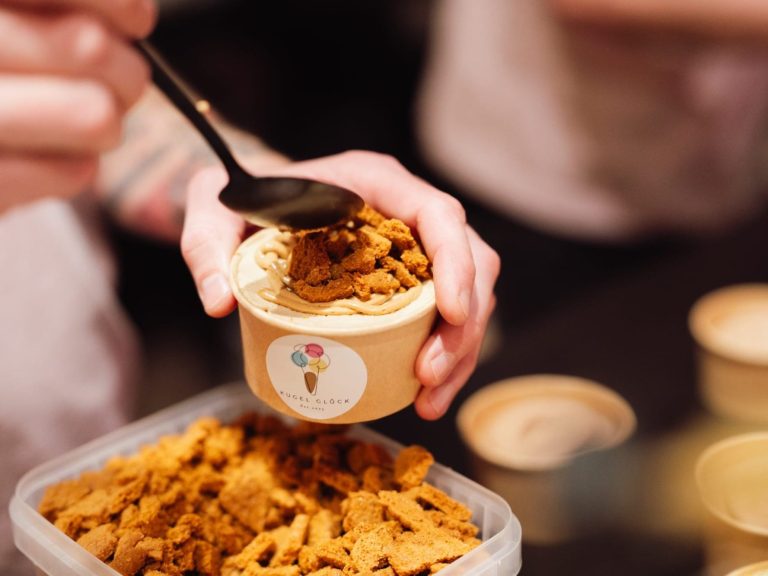 Kugel Glück Dessert Jemand schöpft Keksstückchen auf ein Tiramisu in einem Becher.